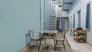 A narrow hallway with a table and chairs, a ladder, and a shelf with shoes. - Hotel O Pondok Karisma Syariah (Tasikmalaya)