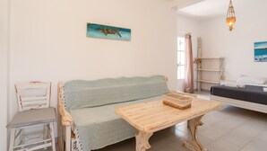 Ett vardagsrum med en soffa, ett träbord, en stol och en säng.