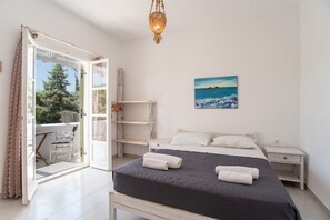 Een slaapkamer met een bed, een schilderij, een nachtkastje, een stoel en uitzicht op de omgeving.