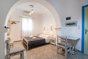 Un dormitorio con cama, mesita de noche, silla, escritorio y un arco en la puerta.