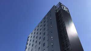 Un moderno edificio de gran altura con un llamativo logotipo 'DR' en el lateral.