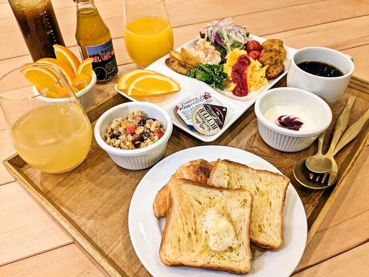 Una bandeja de desayuno con tostadas, fruta y bebidas.