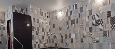 A swimming pool with a tiled wall featuring geometric patterns.