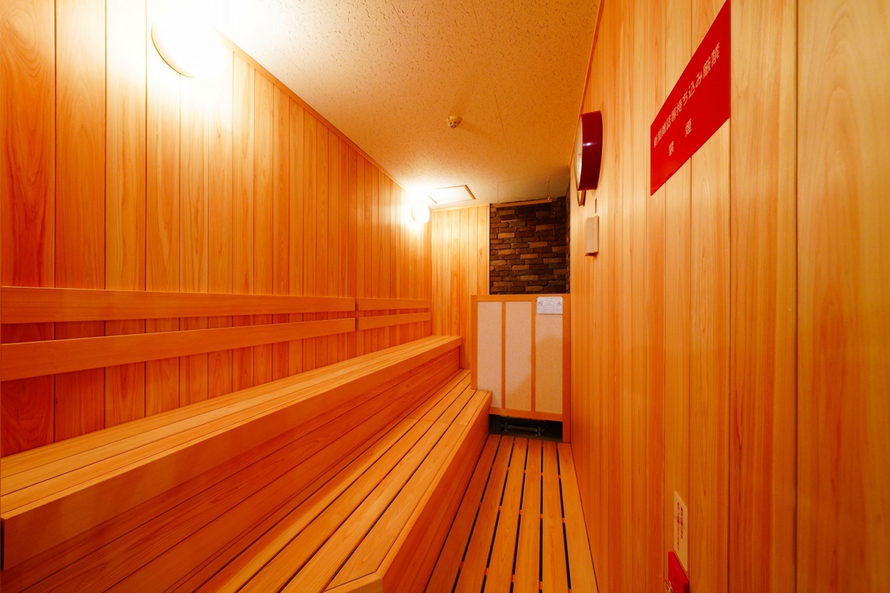 A wooden sauna with benches and a stone wall.