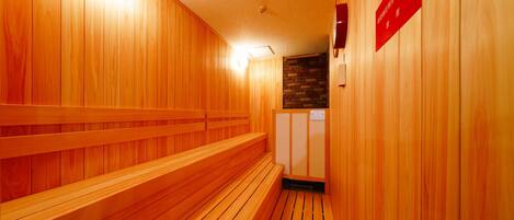 A wooden sauna with benches and a stone wall.