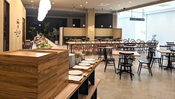 Un restaurante con varias mesas y sillas, una barra de madera y una zona de bufé.