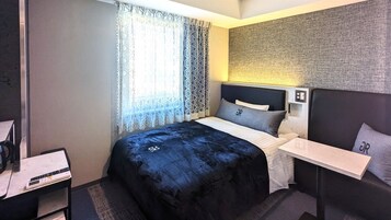 A modern hotel room with a bed, bedside table, and a headboard with a textured wall.