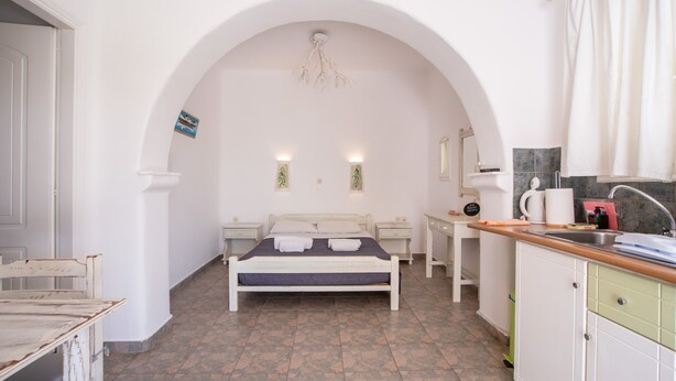 Een slaapkamer met een bed, nachtkastjes, een bureau en een kitchenette.