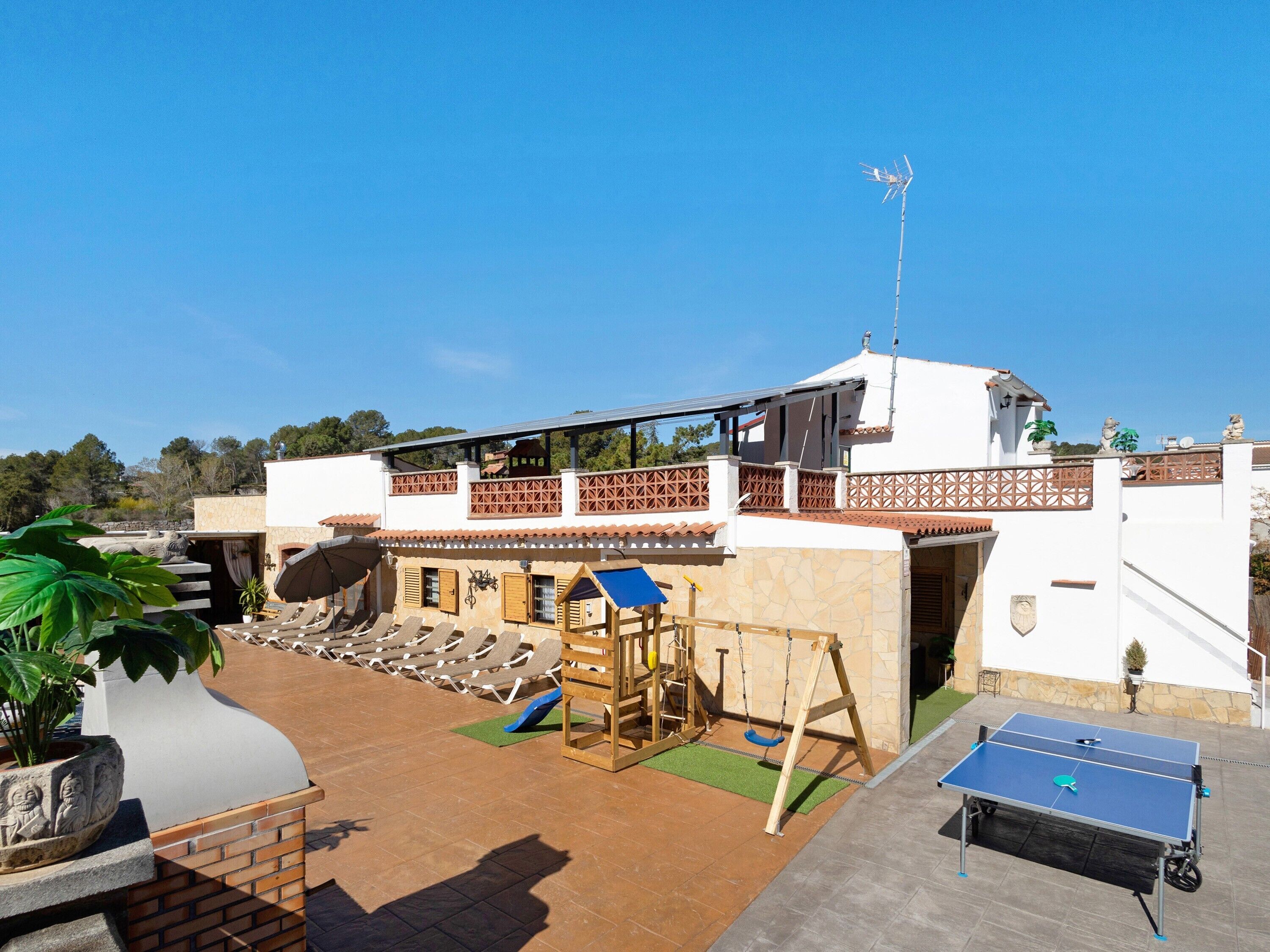 Terraza en la azotea con mesa de ping pong, área de juegos para niños y sillones de descanso.