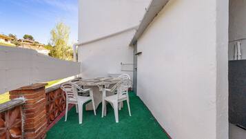 Un pequeño patio al aire libre con una mesa y sillas, un muro de ladrillo y una valla blanca.