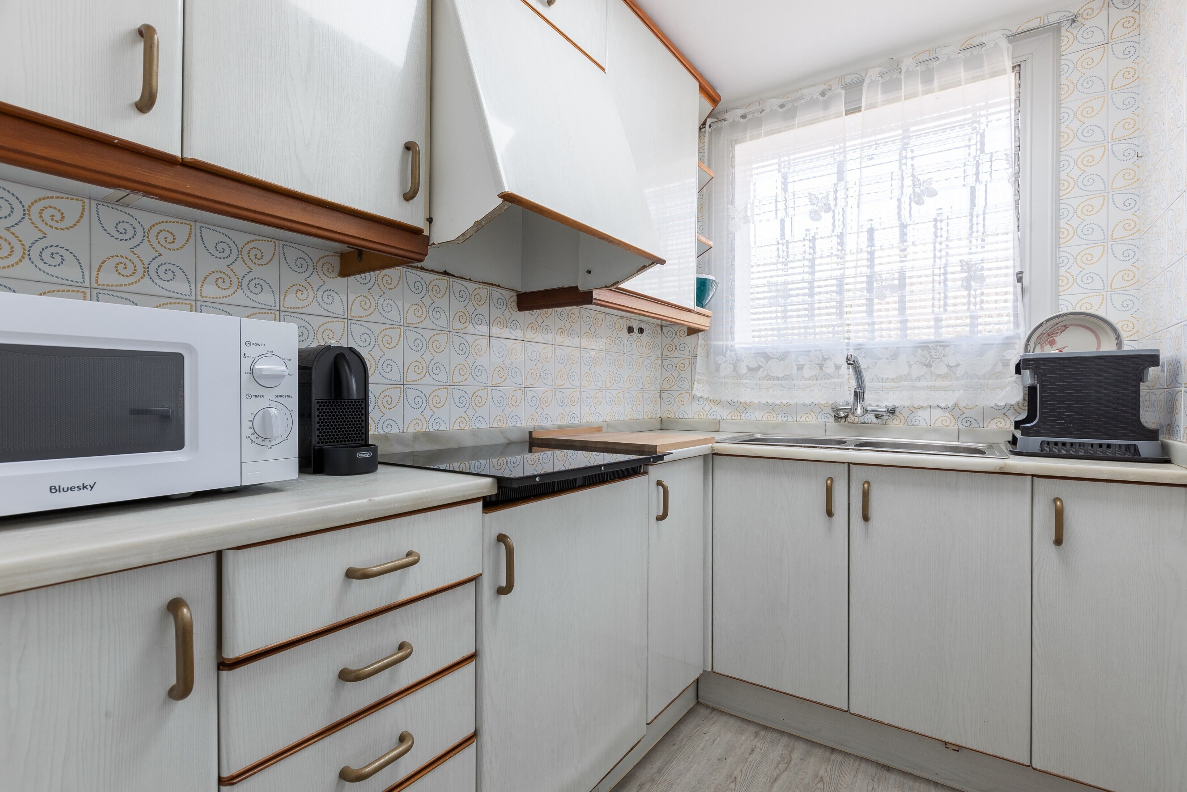 Una cocina con armarios blancos, un microondas, una estufa y un lavabo.