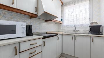 Una cocina con armarios blancos, un microondas, una estufa y un lavabo.