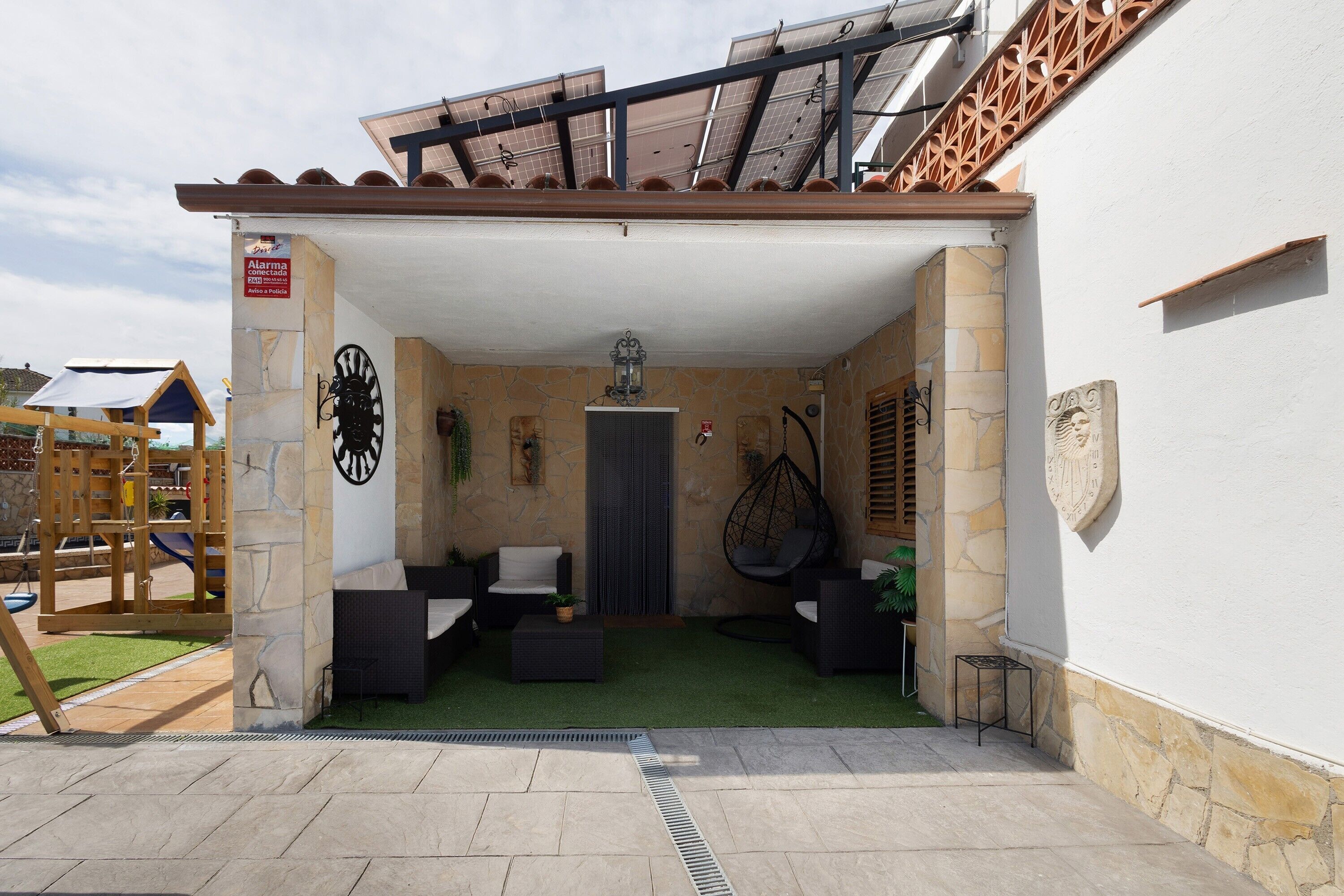 Un patio al aire libre con paredes de piedra, una silla colgante y una pequeña mesa.