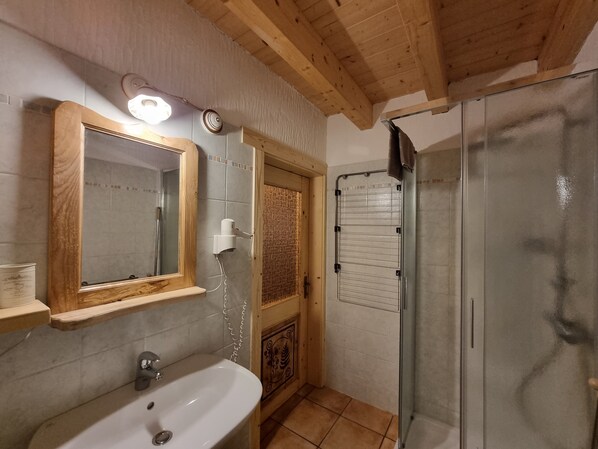 Une salle de bain avec un meuble-lavabo en bois, un évier, un miroir, un porte-serviettes et un espace douche.