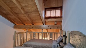 A loft-style bedroom with a wooden ceiling, a small window, and two beds with headboards. - Beautiful 'Adamello 7' Apartment with Wi-Fi (Pinzolo)