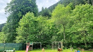 A playground with slides and swings, surrounded by lush greenery and trees. - Beautiful 'Adamello 7' Apartment with Wi-Fi (Pinzolo)