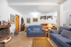 A living room with a blue sofa, a fireplace, and a wooden cabinet.