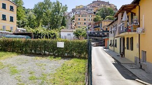 Una calle estrecha flanqueada por edificios, un puente y una colina al fondo.