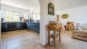 Une cuisine moderne avec des meubles de couleur sombre, un buffet en bois et un canapé beige dans un salon lumineux.