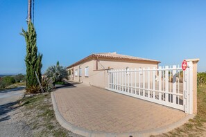 Ein Haus mit einem verschlossenen Einfahrtsweg, blauem Himmel und Blick auf die Landschaft.