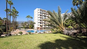 Ein Hotel mit Pool, Palmen und Bergen im Hintergrund.