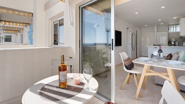 Ein Balkon mit Tisch, Stühlen, einer Flasche und einer Kerze.