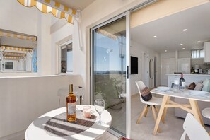Un balcon avec une table, des chaises, une bouteille et une bougie.