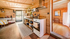 Een houten cabinemeubilair met keuken, eethoek en uitzicht door een deur.