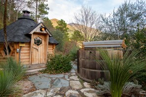 A wooden cabin with a hexagonal window, a stone pathway, and a wooden barrel.