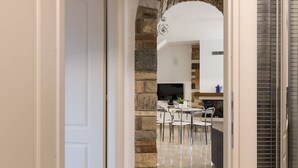 Un acceso a un comedor con pared de piedra, televisor de pantalla plana y suelo de baldosas.