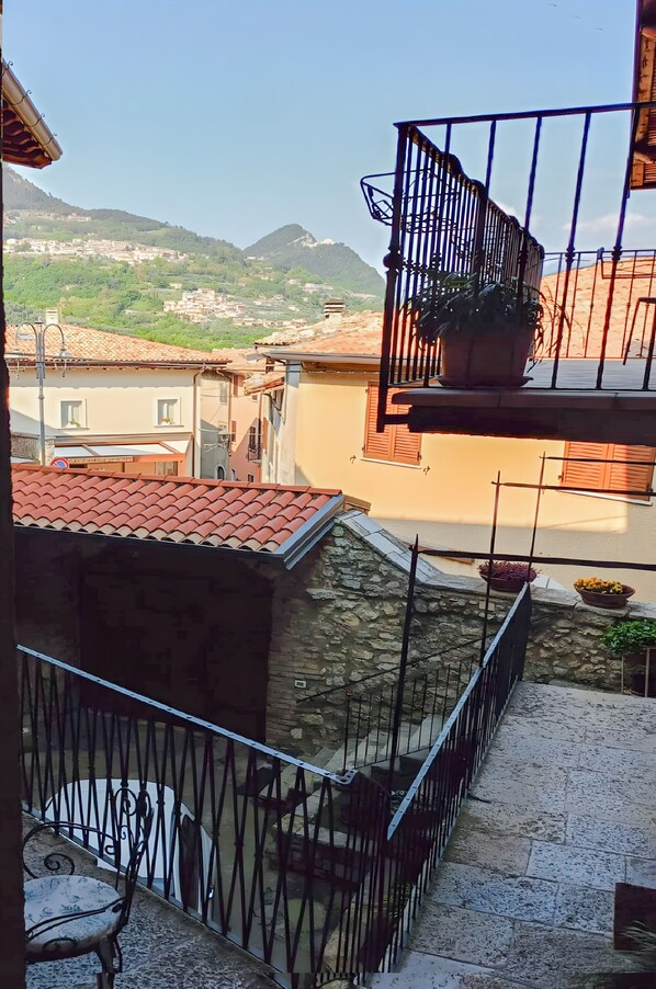 Un balcon donnant sur la ville, avec des murs en pierre et des plantes en pot.