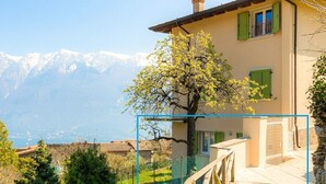 A house with a view of mountains, a tree, and a wooden deck. - Apartment 'El Pià' with Lake View and Private Garden (tignale)