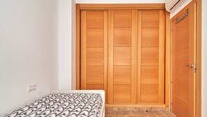A bedroom with a bed, a wooden wardrobe, and a door. - Holiday Apartment "Vivienda Con Piscina" with Private Pool, 3 Terraces & Wi-Fi (Nerja)