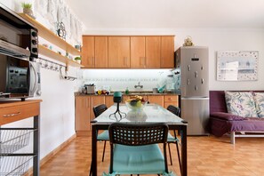 Una cocina compacta con armarios de madera, una mesa de comedor de vidrio y un refrigerador.