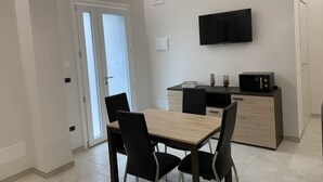 Eine moderne Küche mit einem Holztisch, schwarzen Stühlen, einer Mikrowelle und einem Fernseher an der Wand.