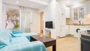 A compact living space with a sofa, a small table, a TV, a washing machine, and a kitchenette. - Holiday Home with Private Pool and A/C near Seville (La Rinconada)