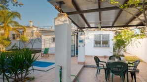 A covered patio with a pool, outdoor seating, and potted plants. - Holiday Home with Private Pool and A/C near Seville (La Rinconada)