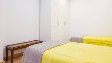 Un dormitorio con una cama, un banco de madera y un armario.