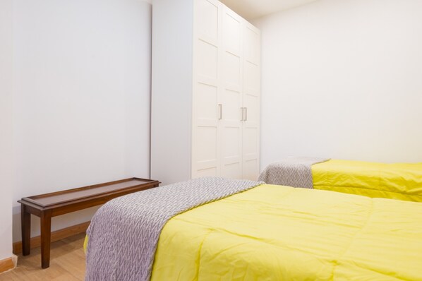 A bedroom with a bed, a wooden bench, and a wardrobe. - Holiday Home with Private Pool and A/C near Seville (La Rinconada)