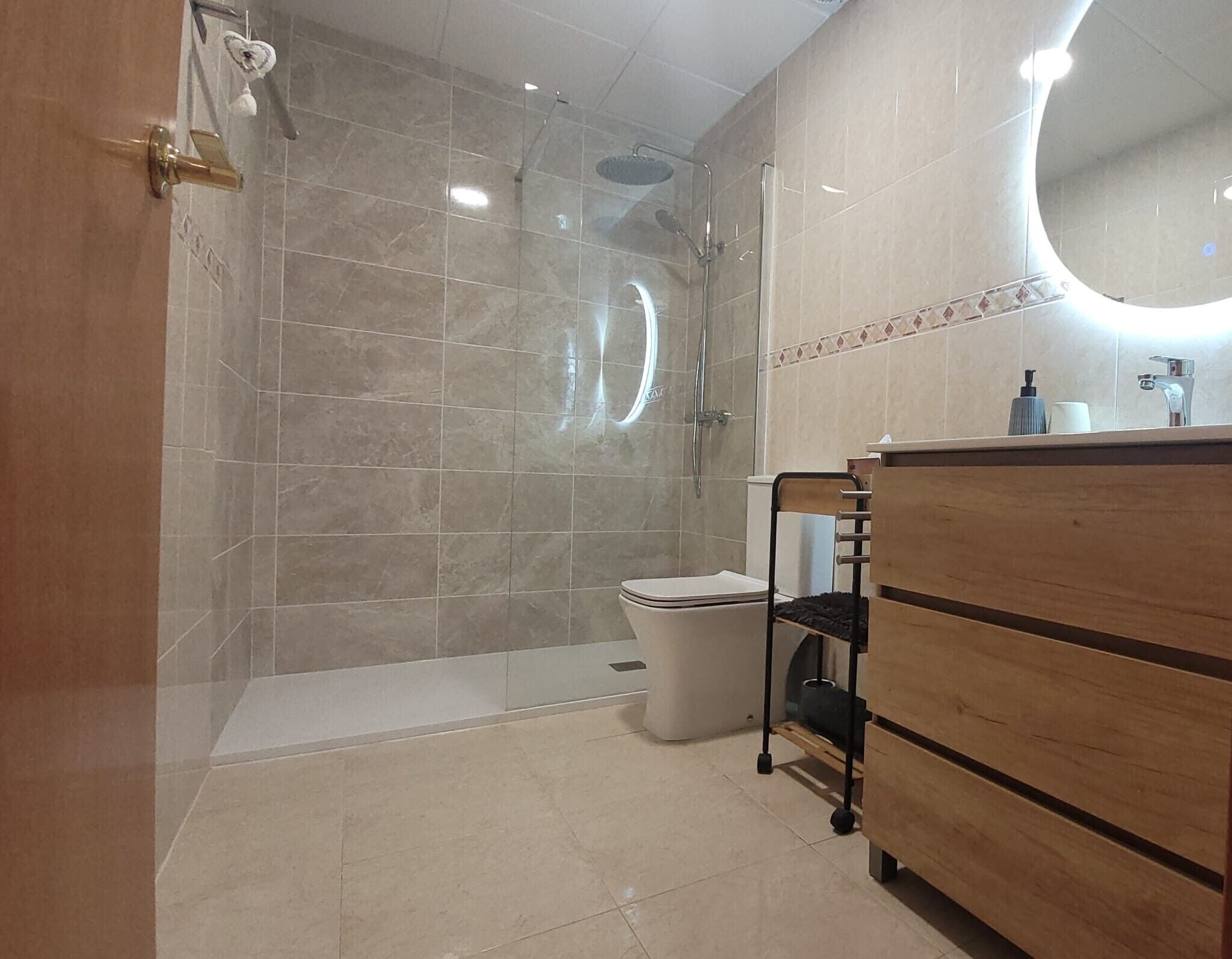 Un baño moderno con ducha, inodoro y tocador de madera.