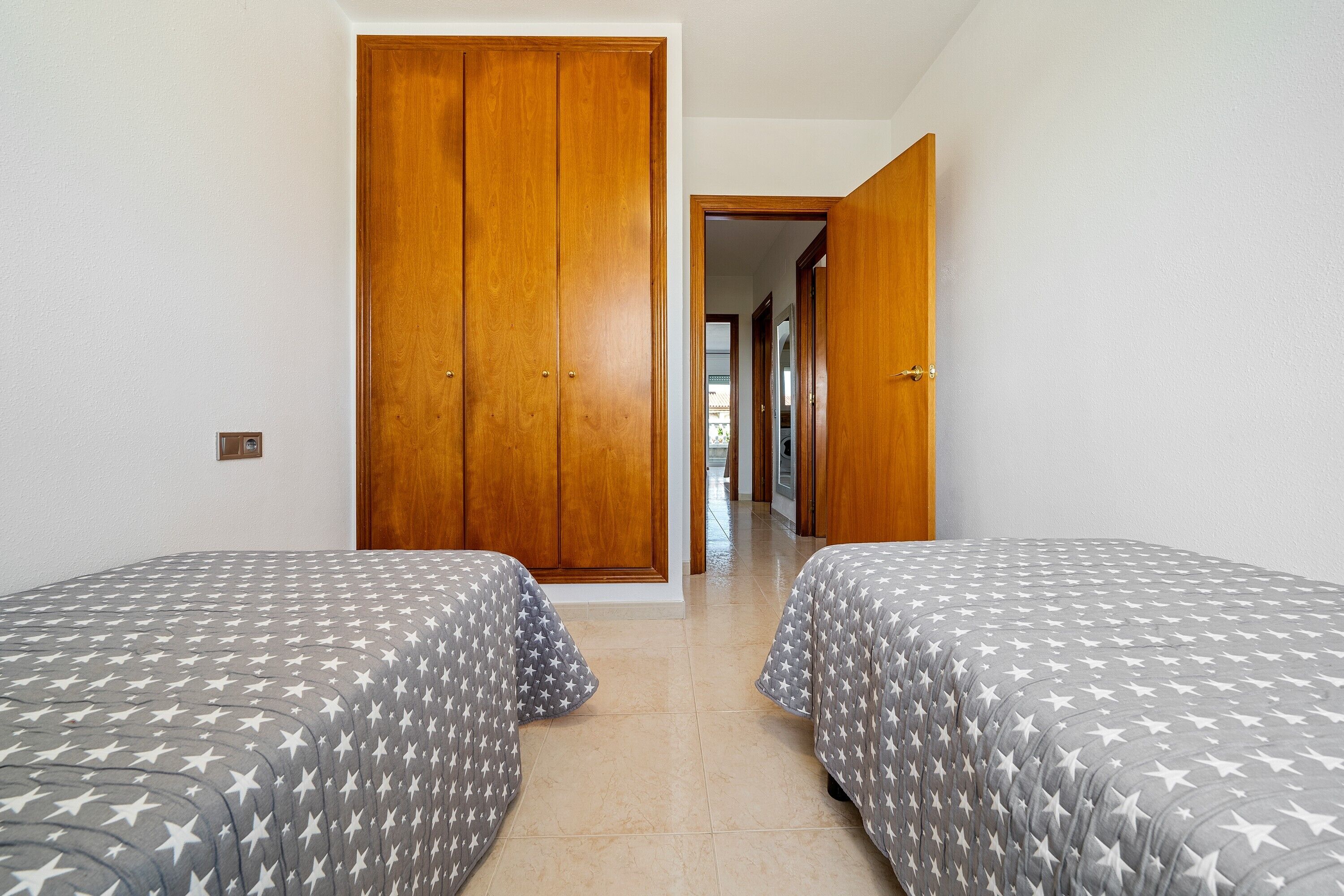 Ein Schlafzimmer mit zwei Betten, einem Holzschrank und einem Flur, der in einen anderen Raum führt.
