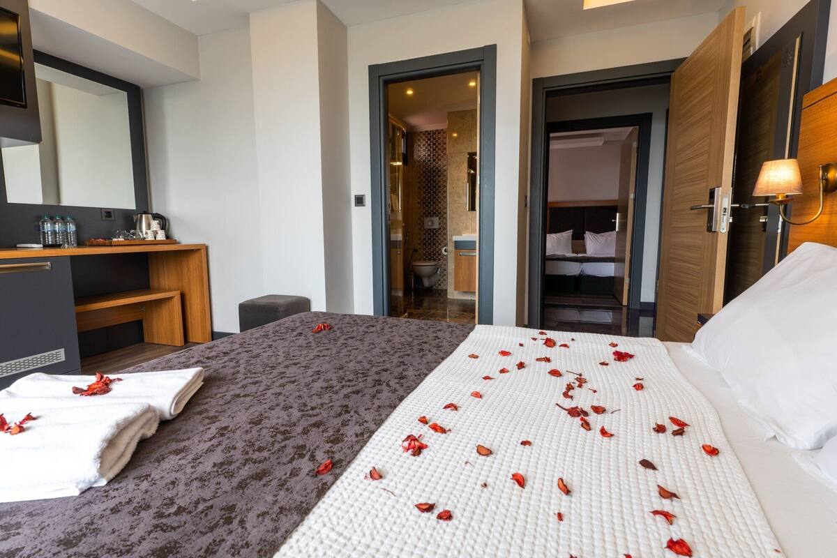 A hotel room with a bed, a desk, a mirror, and a bathroom visible through an open door.