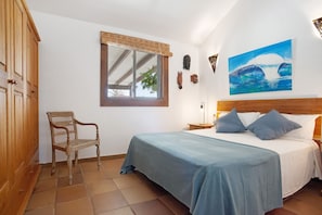 Ein Schlafzimmer mit Bett, Stuhl, Fenster und einem Bild an der Wand.