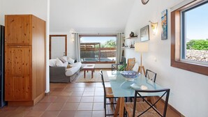 Un espacio habitable compacto con comedor, un sofá, un mueble de madera y un ventanal con vistas.