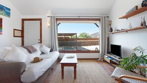 Una sala de estar con un sofá, una mesa de centro, un televisor y un balcón con vistas.