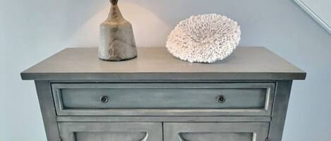 Un meuble gris avec deux tiroirs et une lampe sur le dessus.