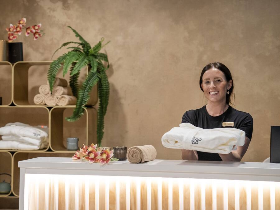 A reception desk with a name tag, a plant, and neatly folded towels.