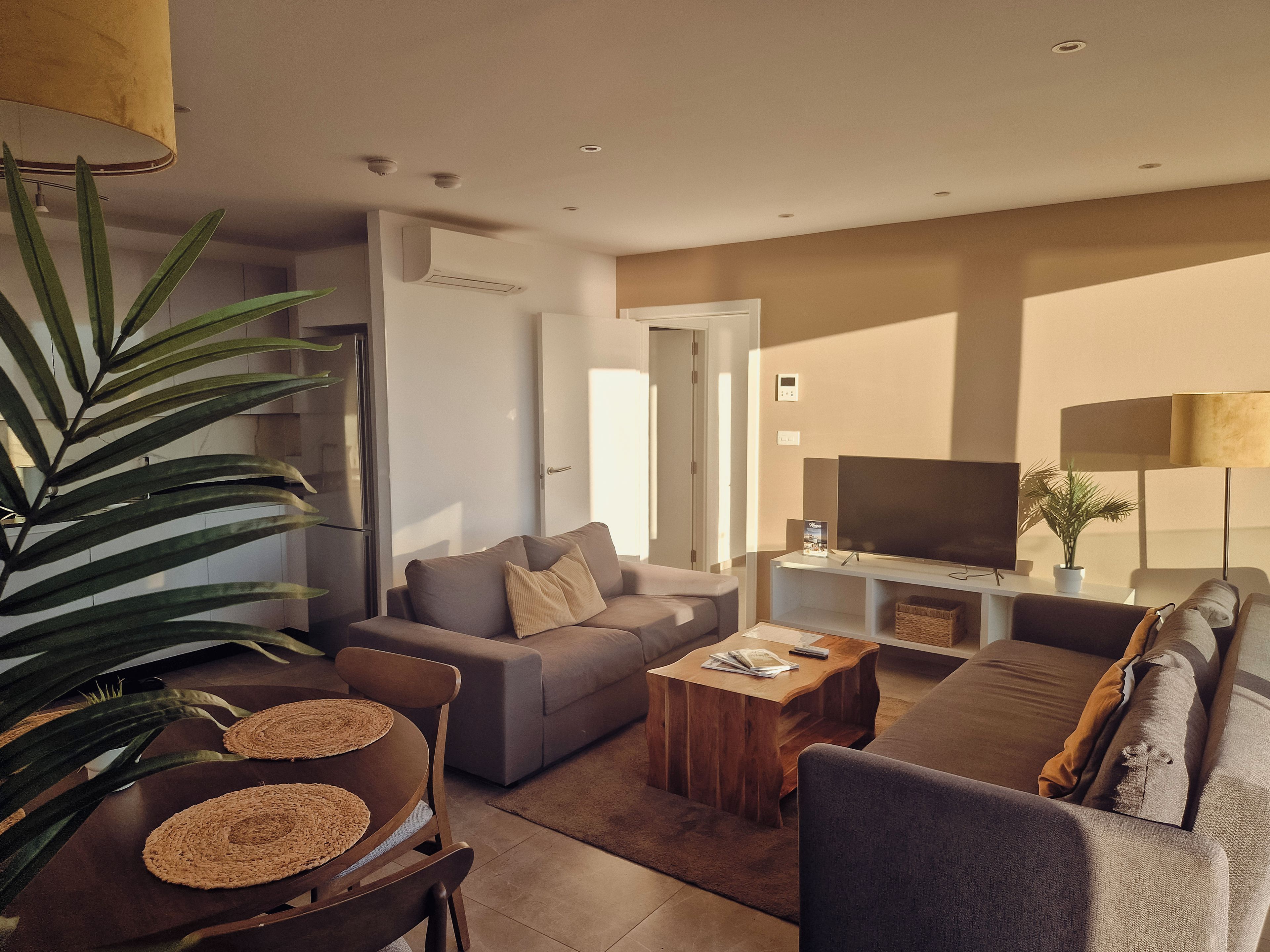 Un salon moderne avec un canapé, une table basse et un téléviseur.
