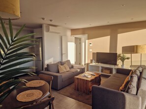 A modern living room with a sofa, coffee table, and television. - E1 Suites & Spa (Gibraltar)