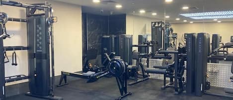 Un gimnasio con diferentes equipos de ejercicio, un espejo grande en la pared y un techo con diseño.
